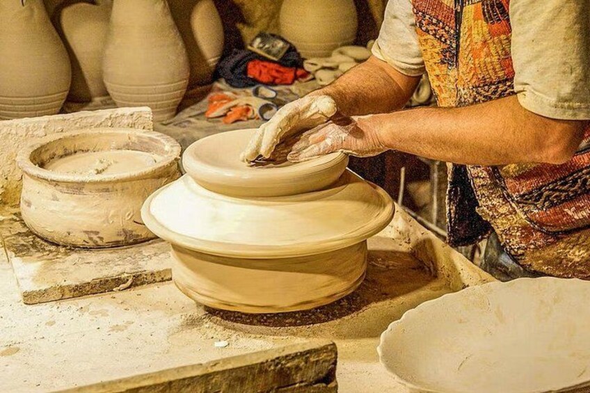 A person shaping a clay pot on a pottery wheel. 4