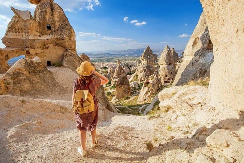 A person walking on a rocky path with unique rock formations and a clear sky. 3