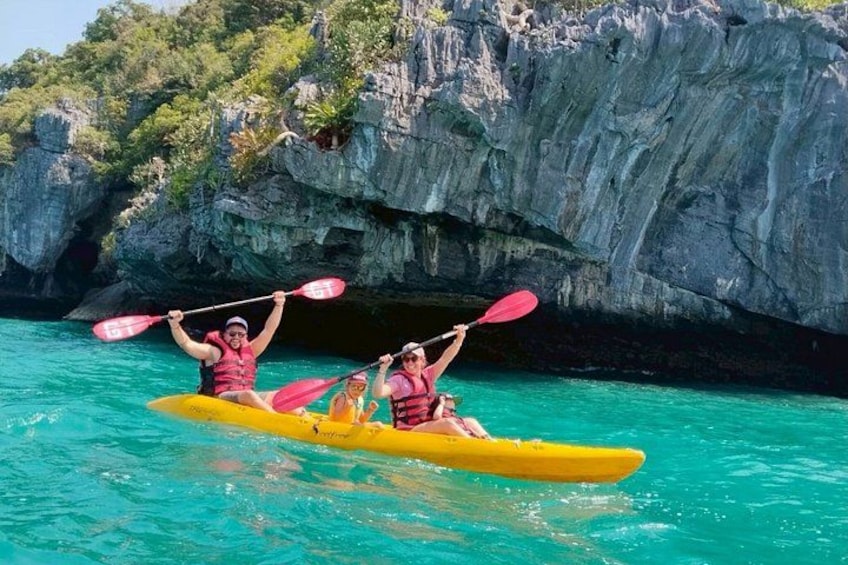 Two people kayaking on turquoise water with rocky cliffs in the background. 2