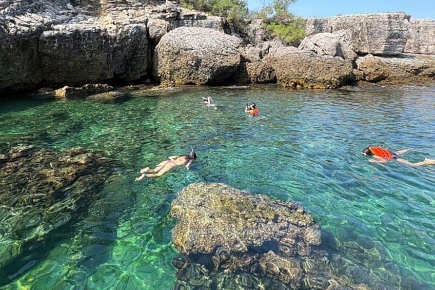 Clear water, people swimming, and rocky formations. 3