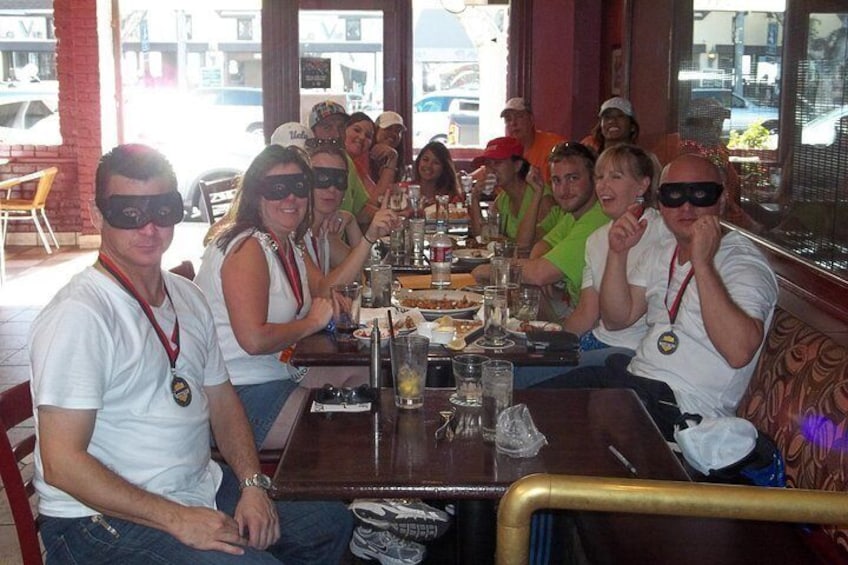 Un groupe de personnes est assis à une table de restaurant, devant de la nourriture et des boissons. 4