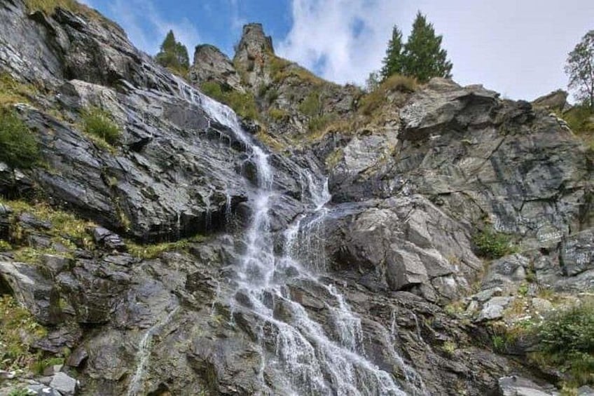 A waterfall cascading over rocky terrain with sparse vegetation. 4