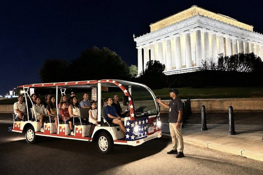 Een touringcar met passagiers en een gids, met de Lincoln Memorial op de achtergrond. 2