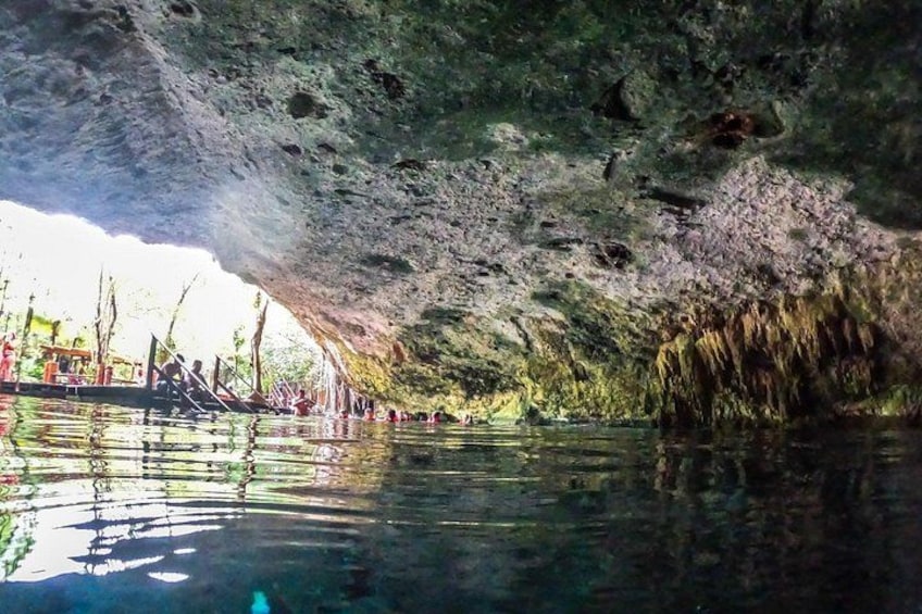 A cave with water reflecting the interior and people swimming. 5