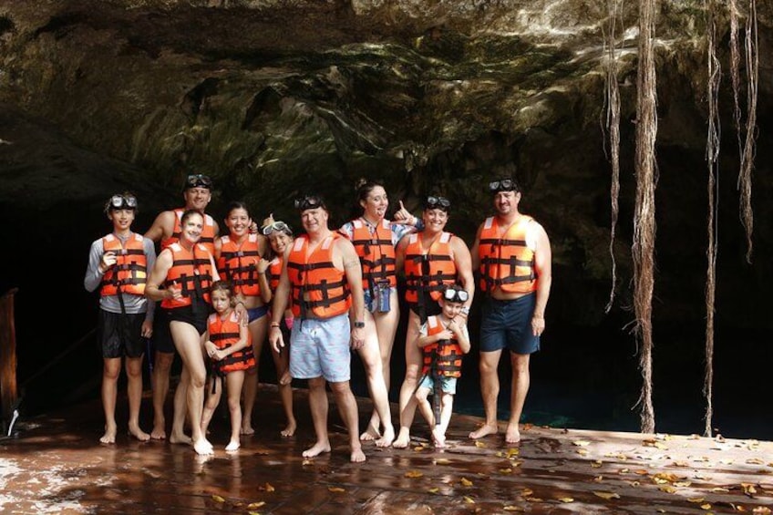 A group of people in orange life jackets standing in a cave. 4