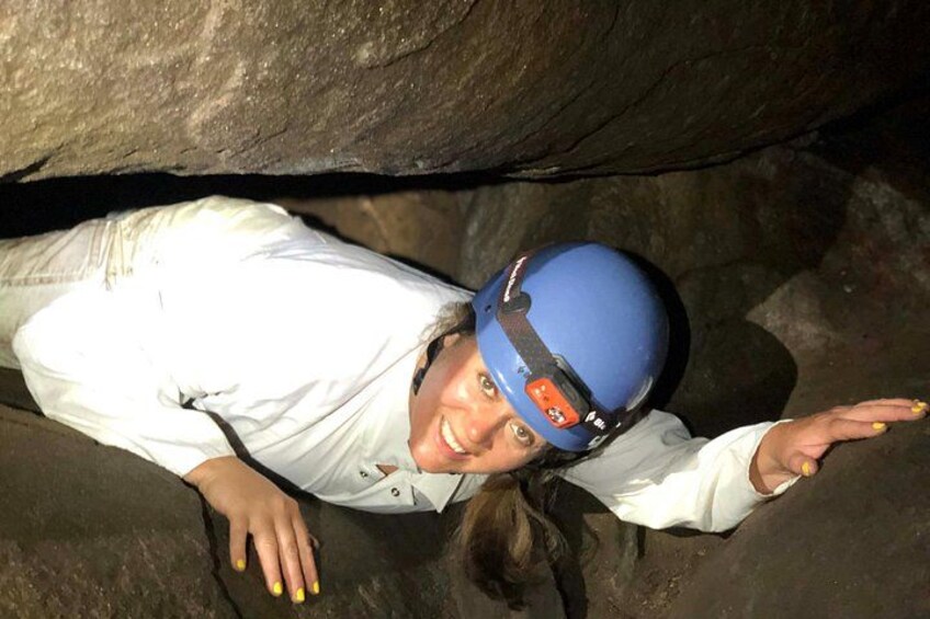 Eine Person mit weißem Hemd und blauem Helm in einer Höhle. 1