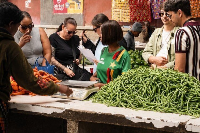 A market scene with people buying vegetables and a weighing scale. 5