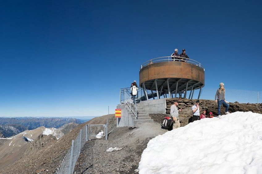 A circular observation tower with people around it, a snowy landscape, and a clear blue sky. 5
