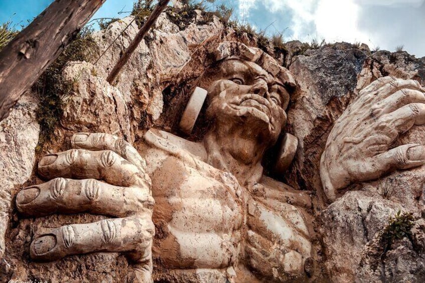 A large rock formation with carved hands and a face. 4
