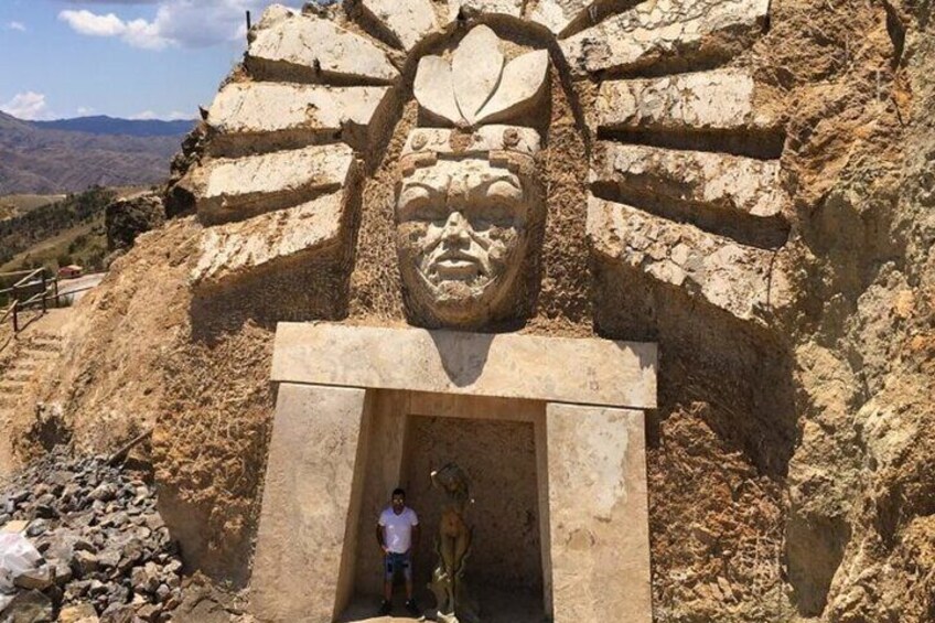 A large stone face carved into a cliff with a person standing in front of it. 2