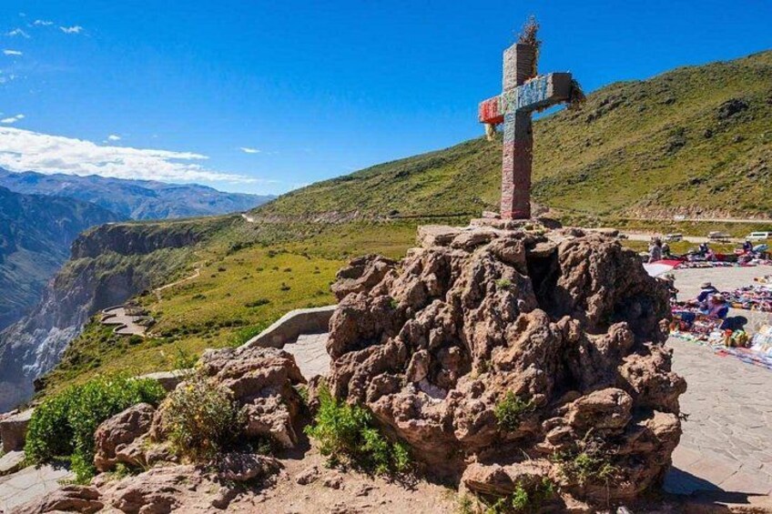 A cross on a rocky outcrop with a valley in the background. 4