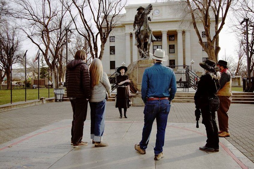 A group of people standing in a park with a statue in the background. 1