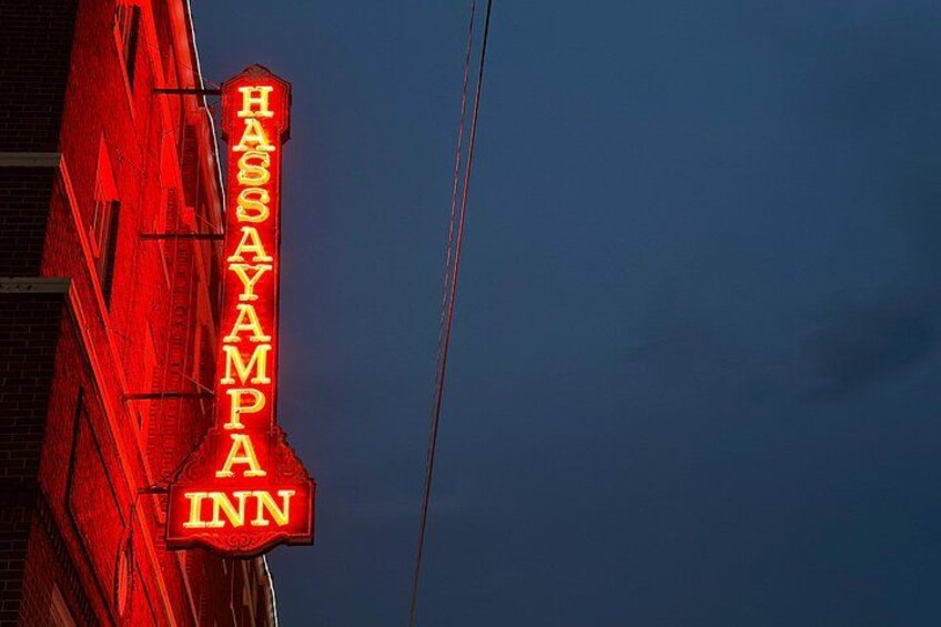 A red building with a neon sign reading 'HASSAYAMPPA INN' against a twilight sky. 3