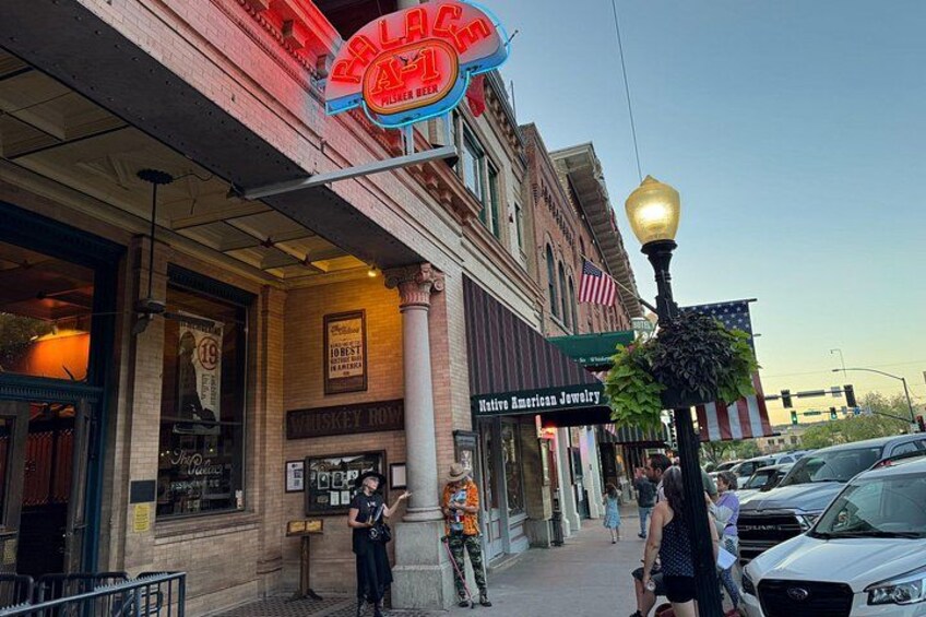 Una strada con un insegna al neon, una segnaletica con scritto 'Whiskey Row' e un negozio di gioielli nativi americani. 4