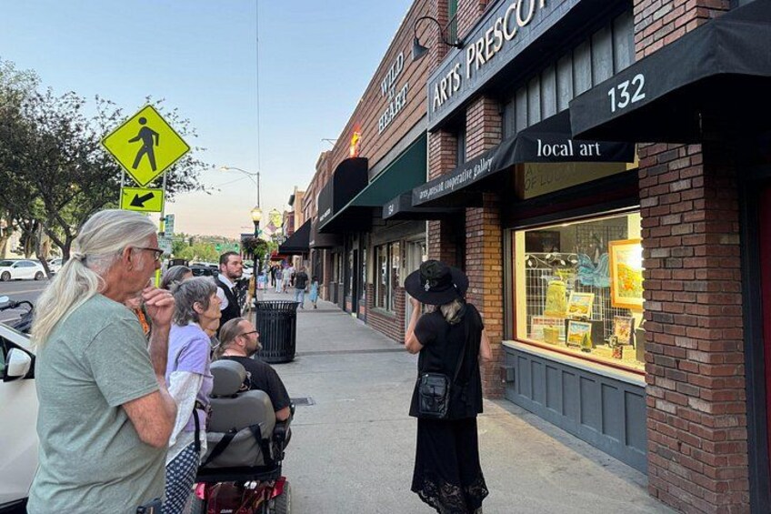Una strada con un segnale di attraversamento pedonale, una vetrina con insegna 'local art' e una persona in piedi accanto al marciapiede. 2