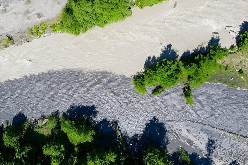 Ein Fluss mit sandigem Ufer, grüner Vegetation und einem kleinen Gebäude in der Nähe des Wassers. 3