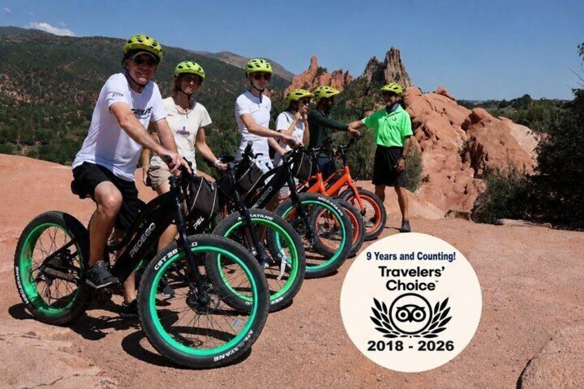 En grupp cyklister på en stenig stig med ett bergigt landskap i bakgrunden. 3