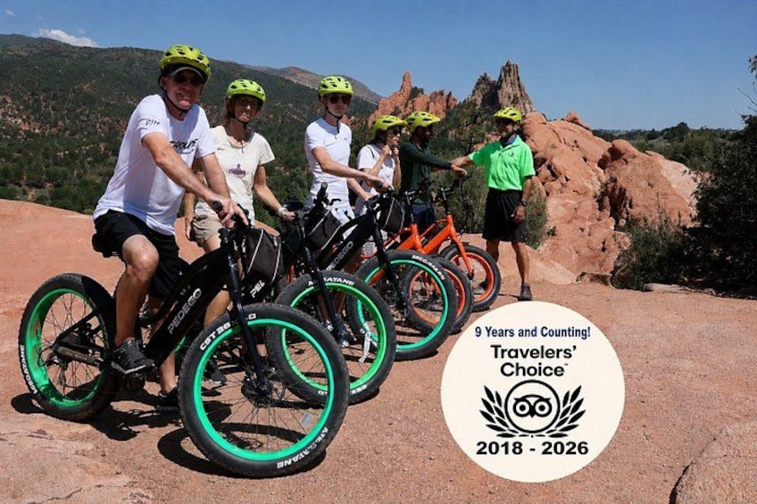 En gruppe mennesker på cykel foran et naturskønt bjerglandskab. 1