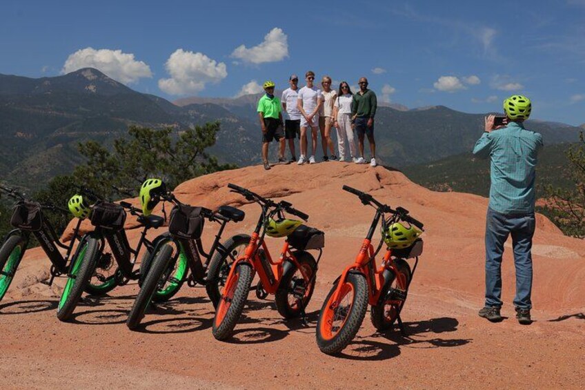 En gruppe mennesker på en bjergtinde med cykler og en fotograf. 3
