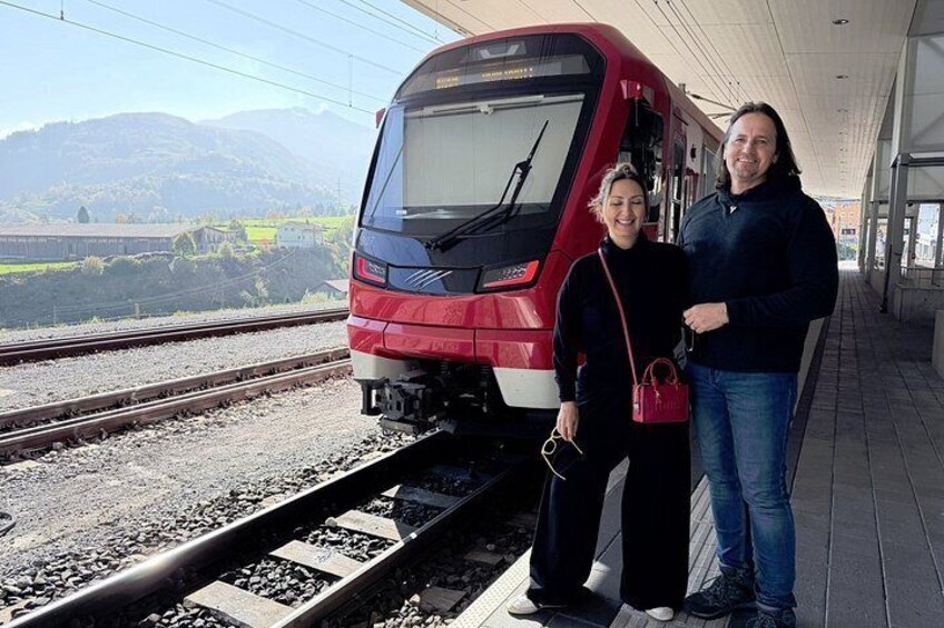 A train at a station with a mountainous landscape in the background. 2