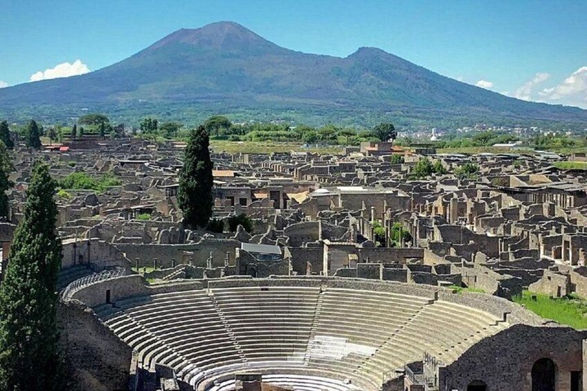 Un antiguo anfiteatro con ruinas y una montaña al fondo. 2