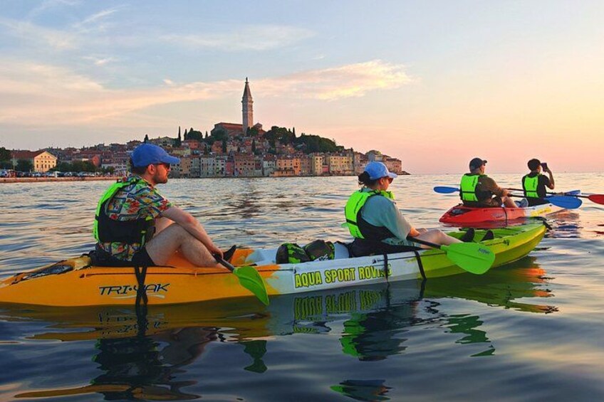 People kayaking on a calm river with a cityscape in the background. 3