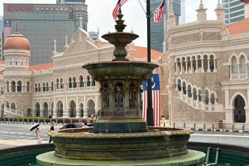 A historic building with a fountain in front, flags, and a modern skyscraper in the background. 4
