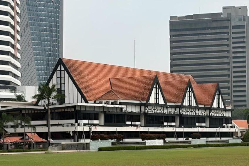 A building with a red roof and white walls, surrounded by modern high-rise buildings. 5