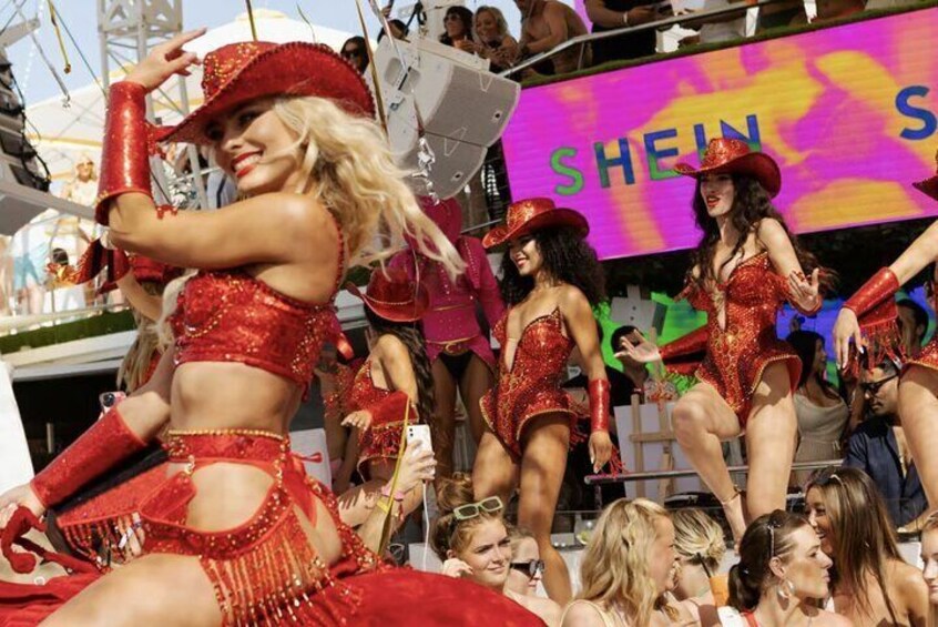 A group of people in red costumes performing on a stage with a SHEIN sign in the background. 4
