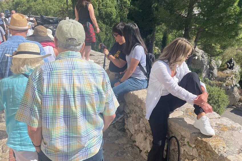 People sitting on stone steps in a park with trees and rocks in the background. 5