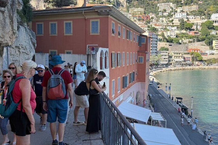 A coastal town with people walking along a cliffside path, overlooking the sea. 2