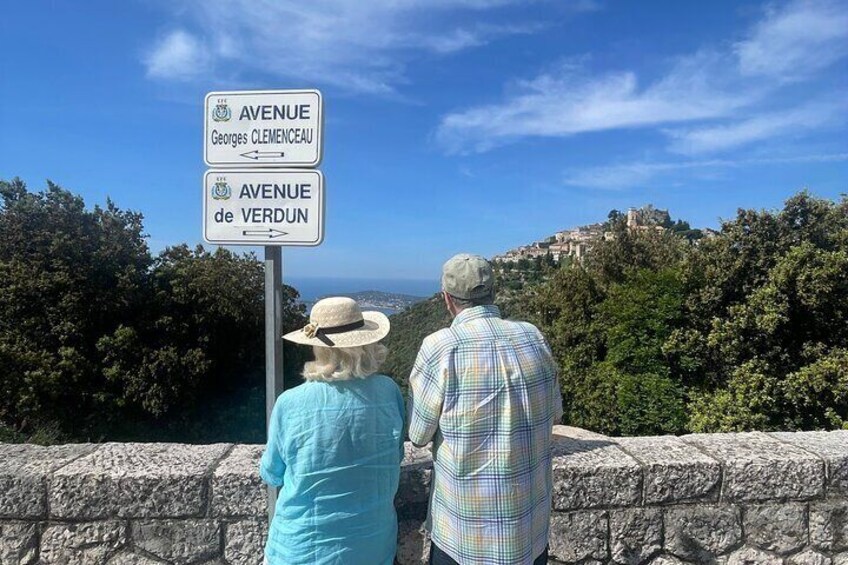 Two people standing by a signpost with directions to 'Avenue Georges Clemenceau' and 'Avenue de Verdun'. 2
