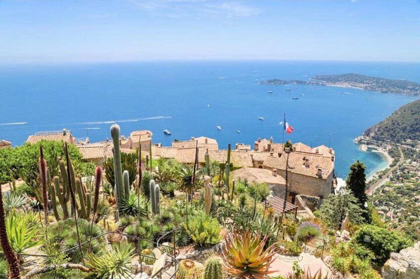 A coastal landscape with a building, cacti, and the sea. 1