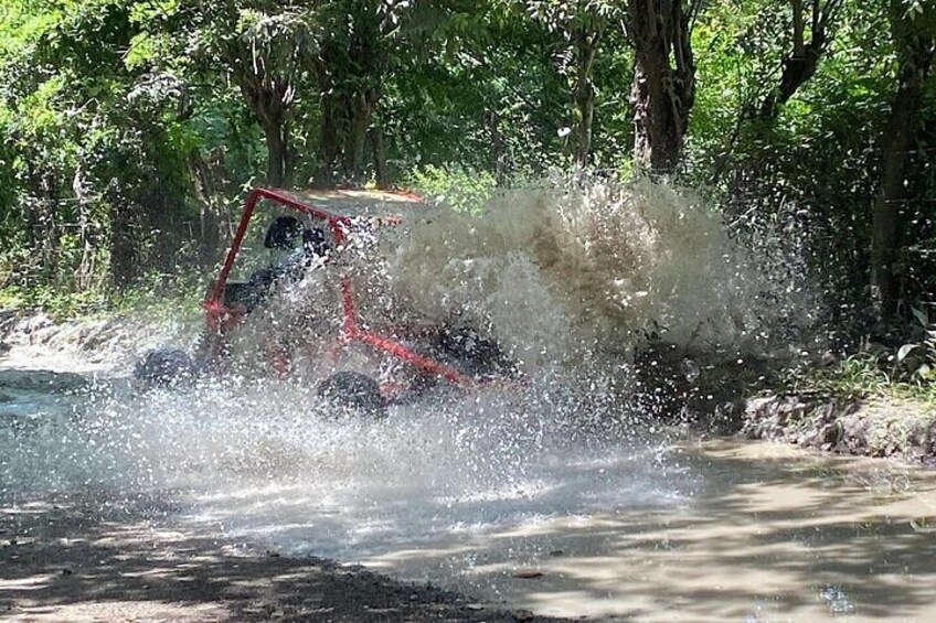 Een voertuig rijdt door een ondiepe waterovergang en spuit water rond. 2