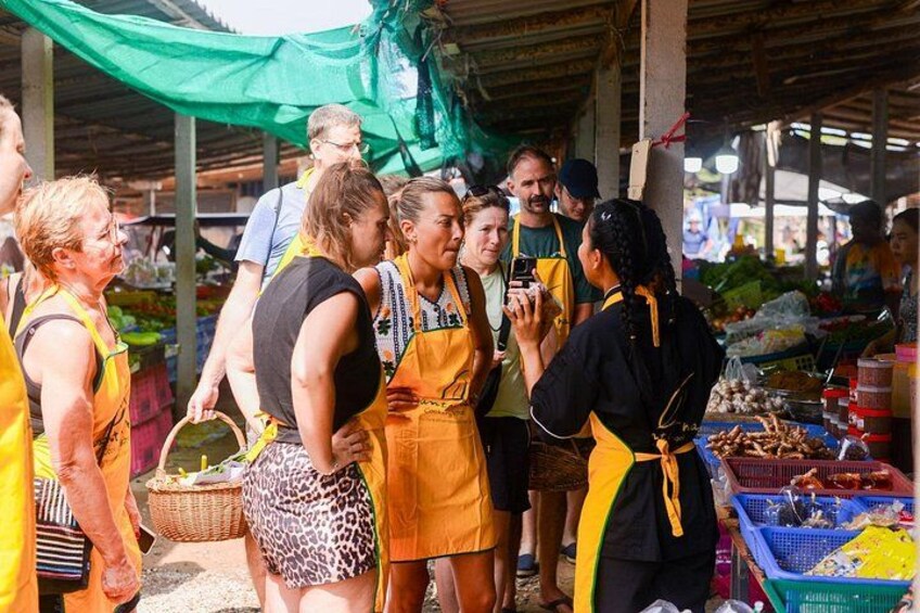 People at a market with yellow aprons, baskets, and various goods. 2