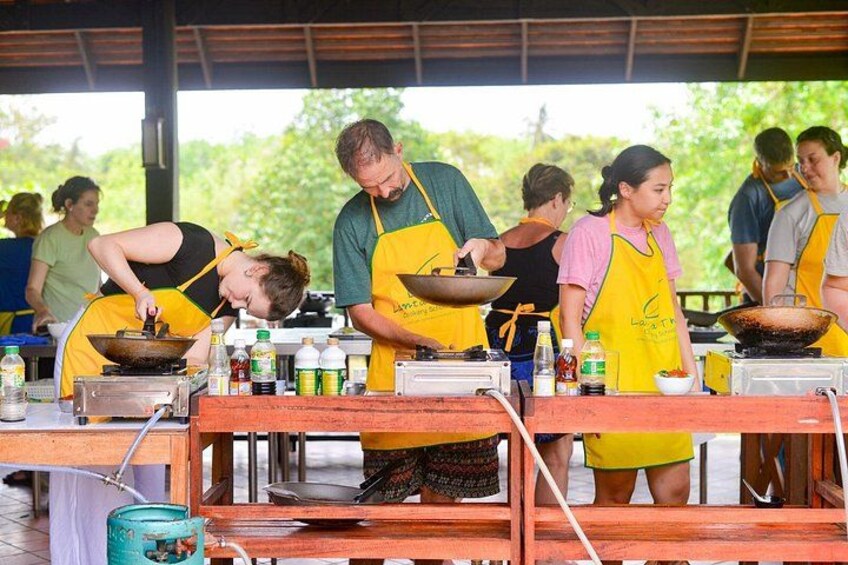 Persone che cucinano all'aperto, con attrezzature e ingredienti. 1