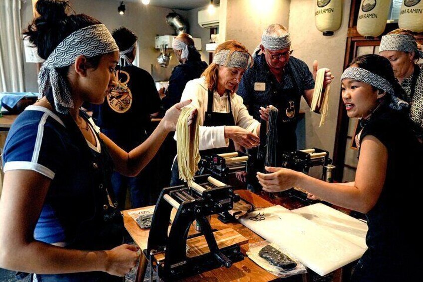 People preparing food, likely noodles, in a kitchen setting. 5