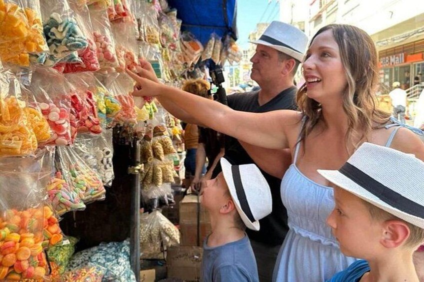 A street market with colorful bags of snacks and a person pointing at them. 5