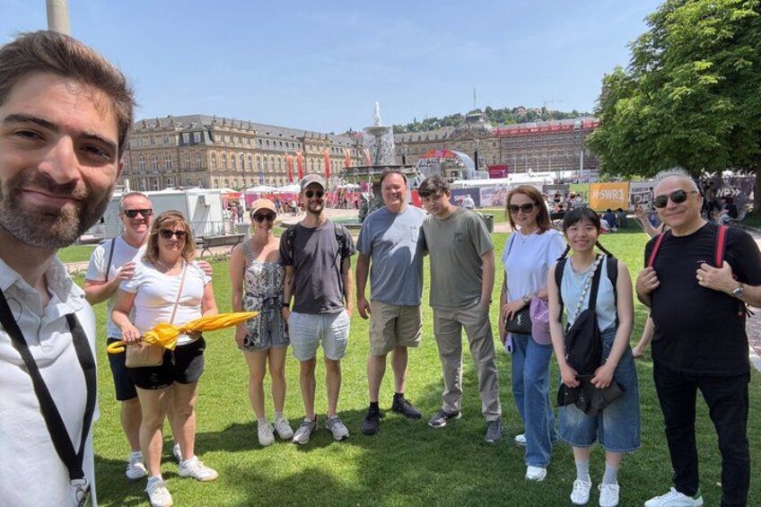 A group of people standing on grass with a building and trees in the background. 4