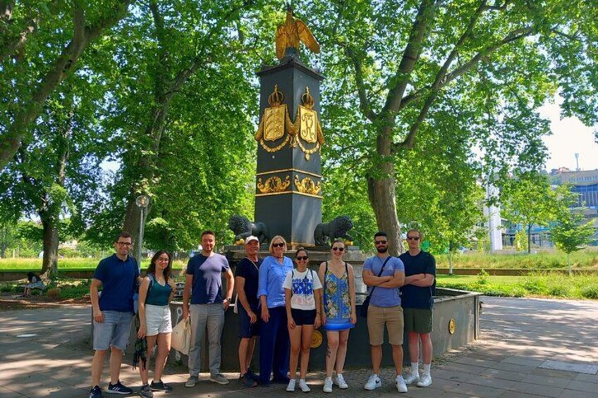 A group of people standing in front of a monument with a golden emblem. 4