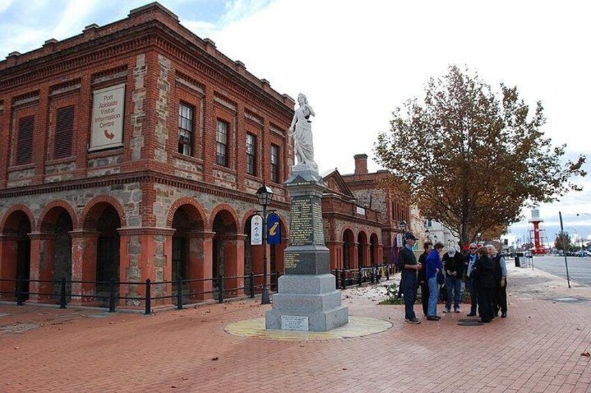 A red brick building with arched windows and a statue in front. 1