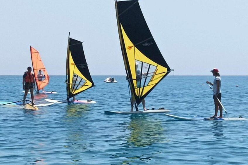 Folk på paddleboards med vinds sejl i vandet. 5