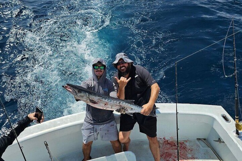 Two people on a boat holding a large fish. 2