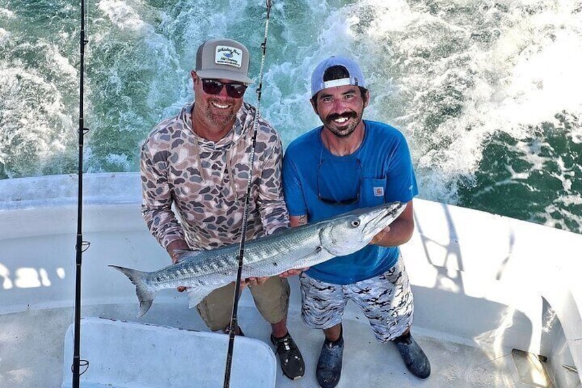 Two people on a boat holding a fish. 1
