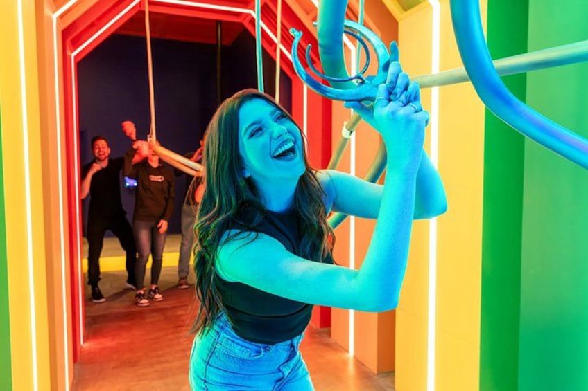 A person swinging on a circular apparatus in a brightly lit indoor space with colorful walls. 2