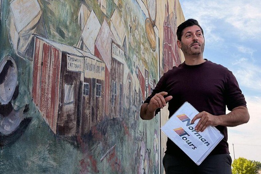 A person holding a brochure titled 'Tour of London' in front of a mural. 5