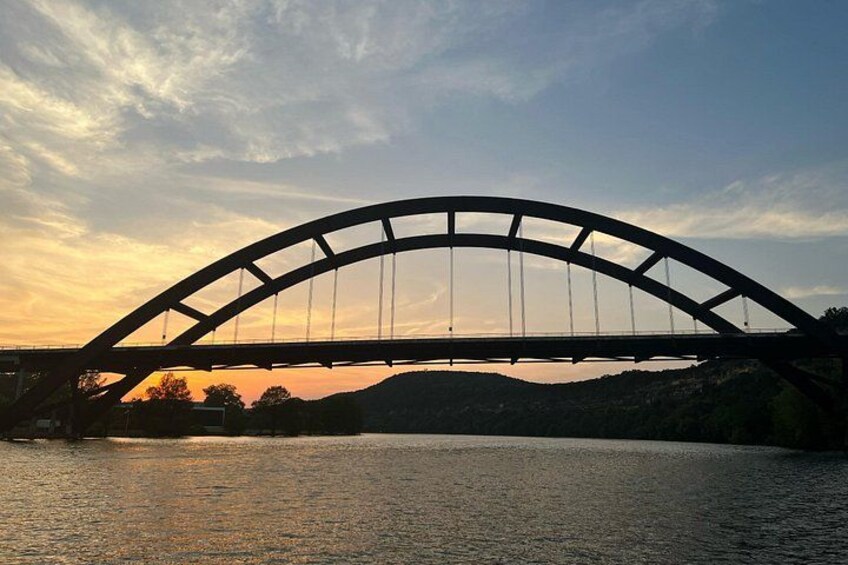 A bridge with a curved arch over a body of water during sunset. 4