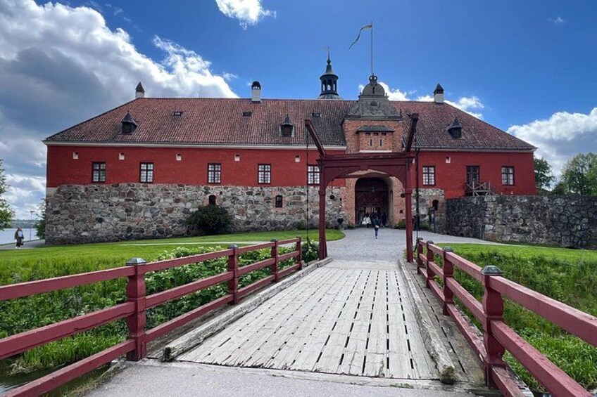 En rød murbygning med en stensokkel, en træbro og en klar blå himmel. 3