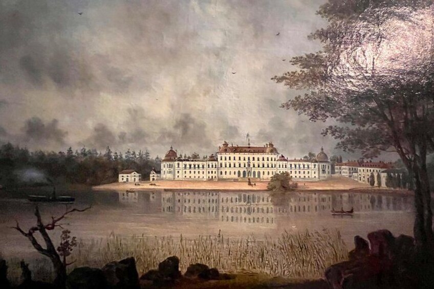 A large building with a reflection in a calm body of water, surrounded by trees and a cloudy sky. 4