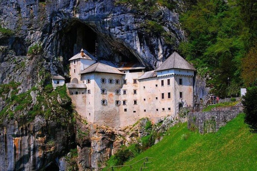 Un château construit à flanc de falaise, entouré de verdure. 2